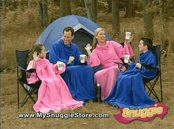 A white family vibing in their snuggies while out camping