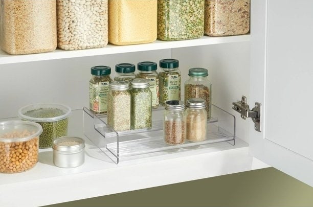 Tiered spice rack shown inside a kitchen cabinet, holding various spice bottles.