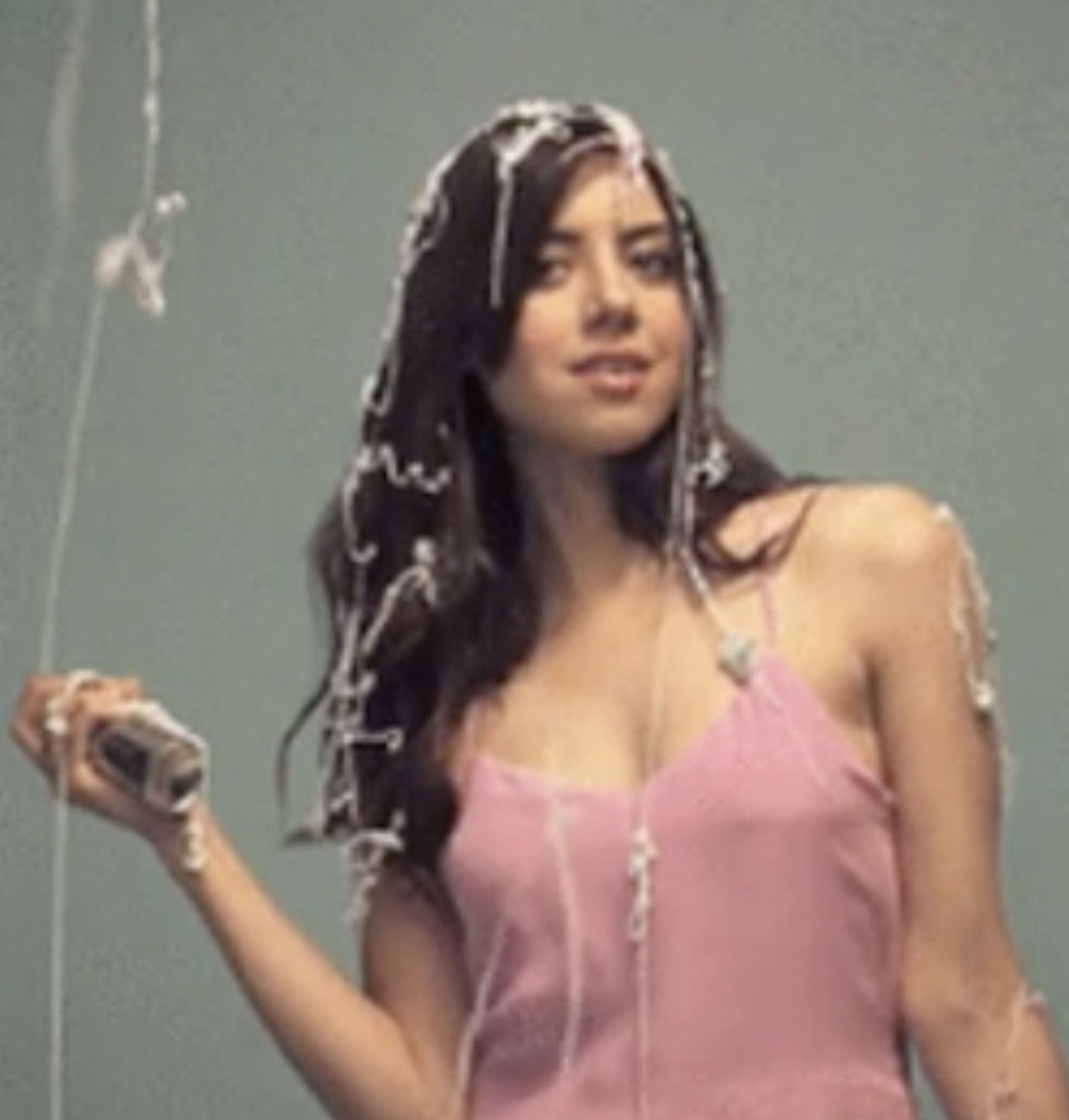 Aubrey Plaza spraying white silly string in the air, landing on her body