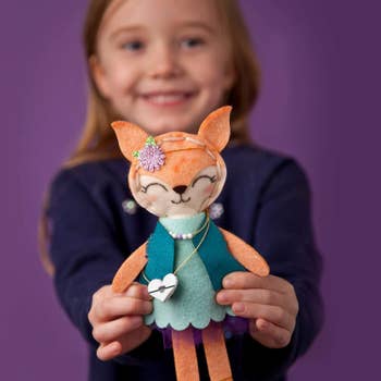 Child model holding felt fox doll 