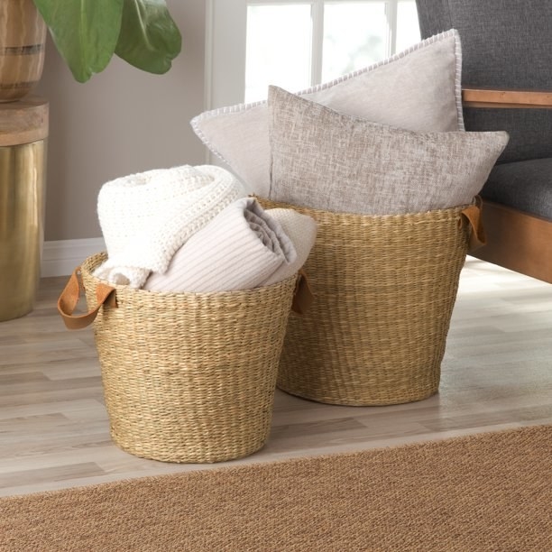 Two baskets holding pillows and blankets.
