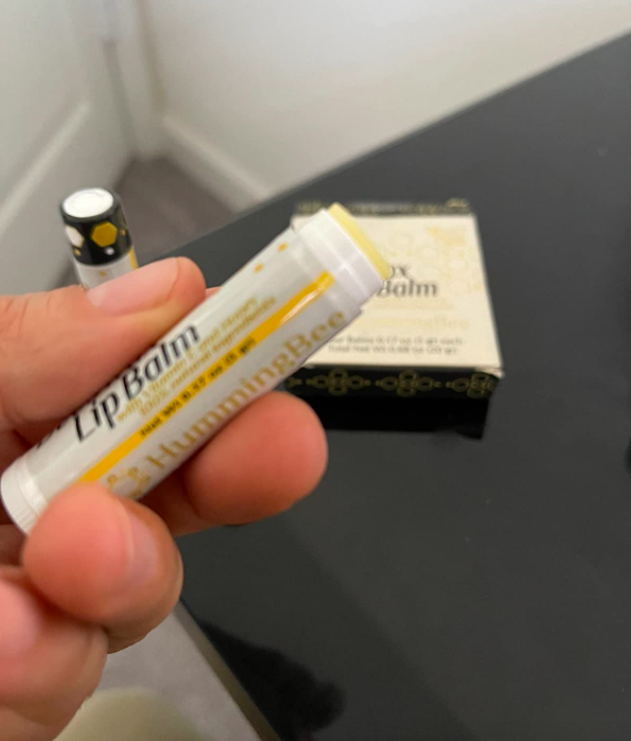 reviewer&#x27;s hand holding the lip balm tube