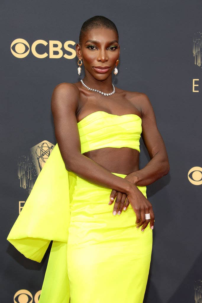 Michaela posing on the EMMYS red carpet in a neon bandeau top with in the back and a matching skirt