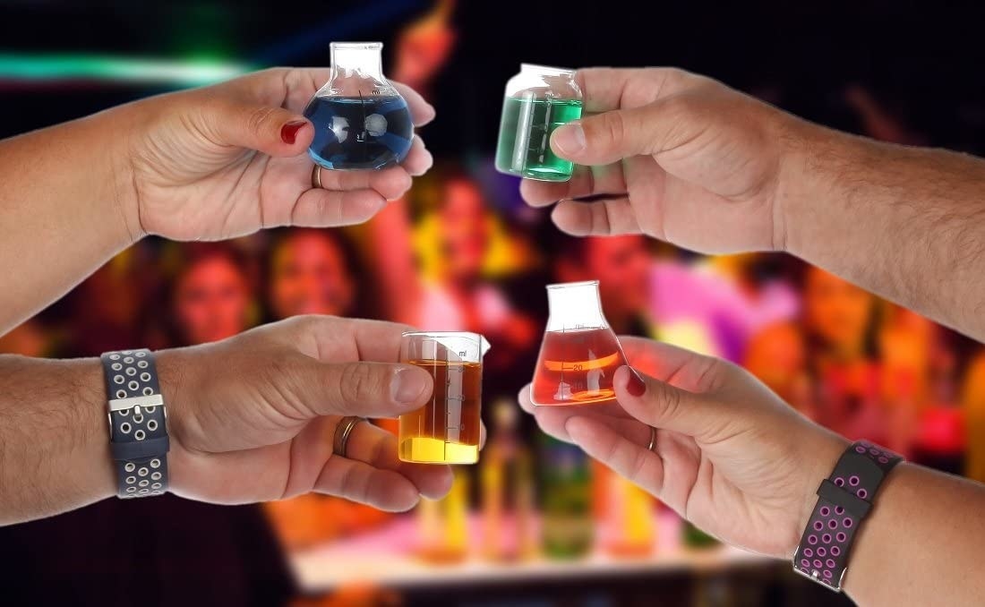four people holding up each shot glass that look like a different style beaker