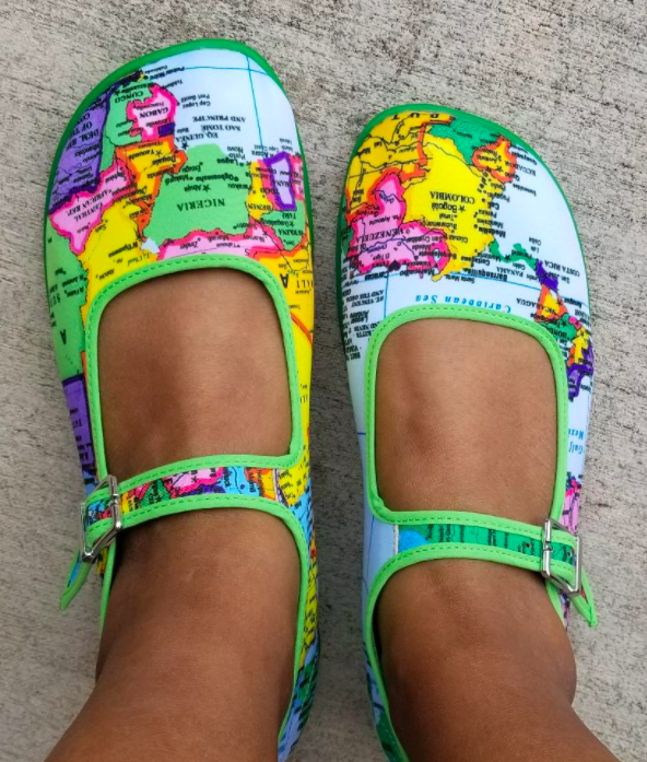 reviewer&#x27;s feet in the Mary Janes with a colorful world map print all over it and bright green trim