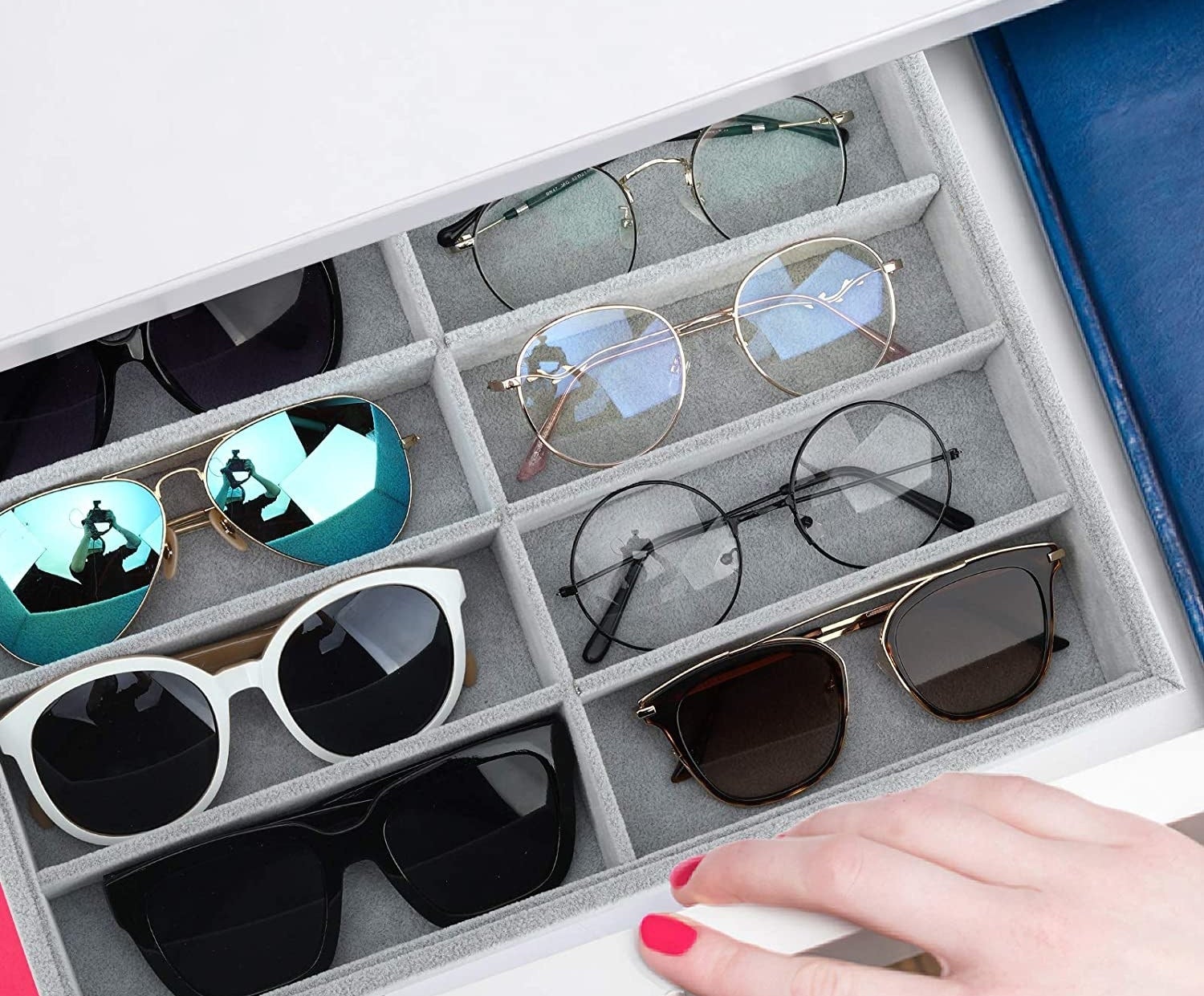 An open drawer with the divided insert inside; its filled with pairs of sunglasses