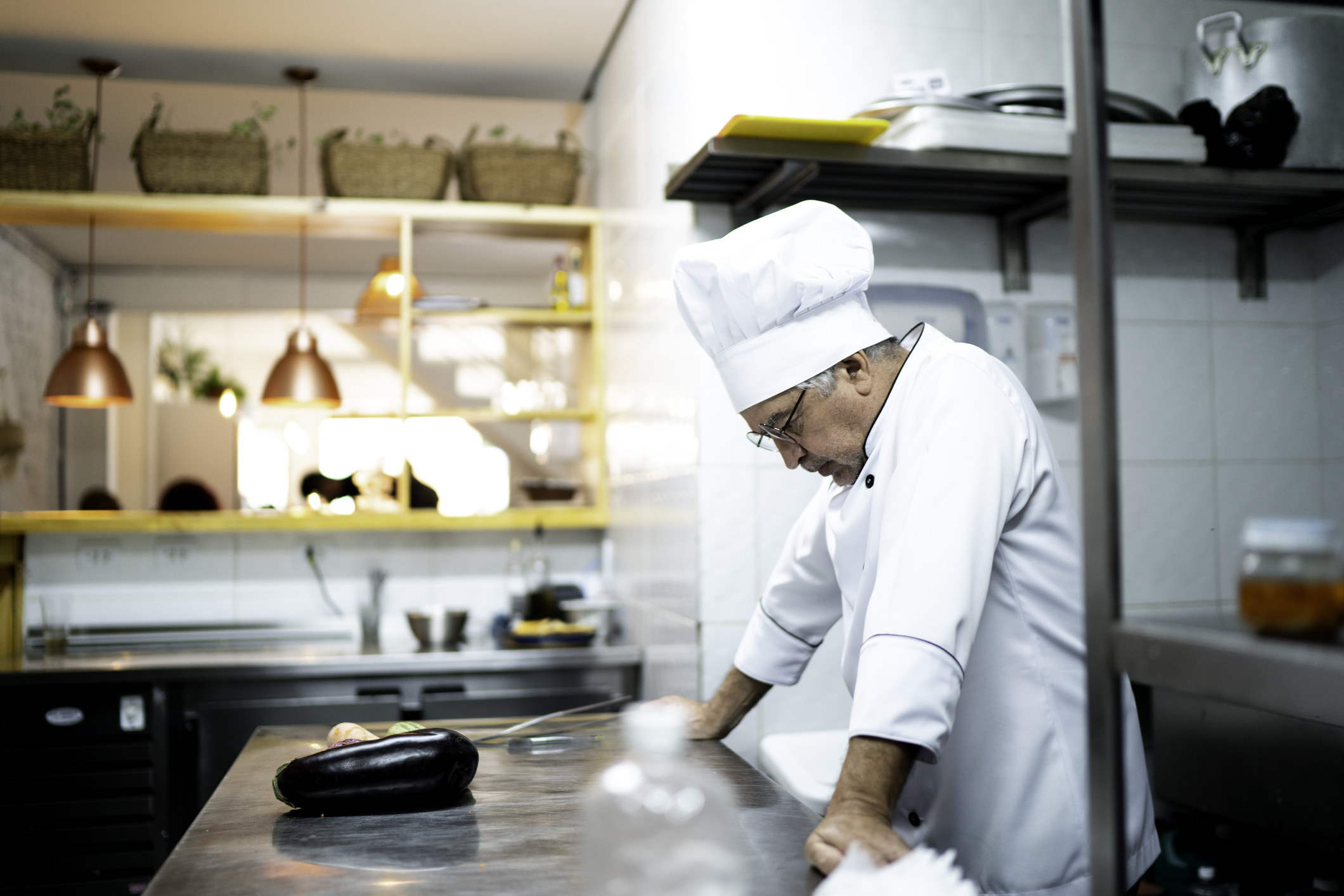 A man wearing a chef&#x27;s hat in the kitchen looking down