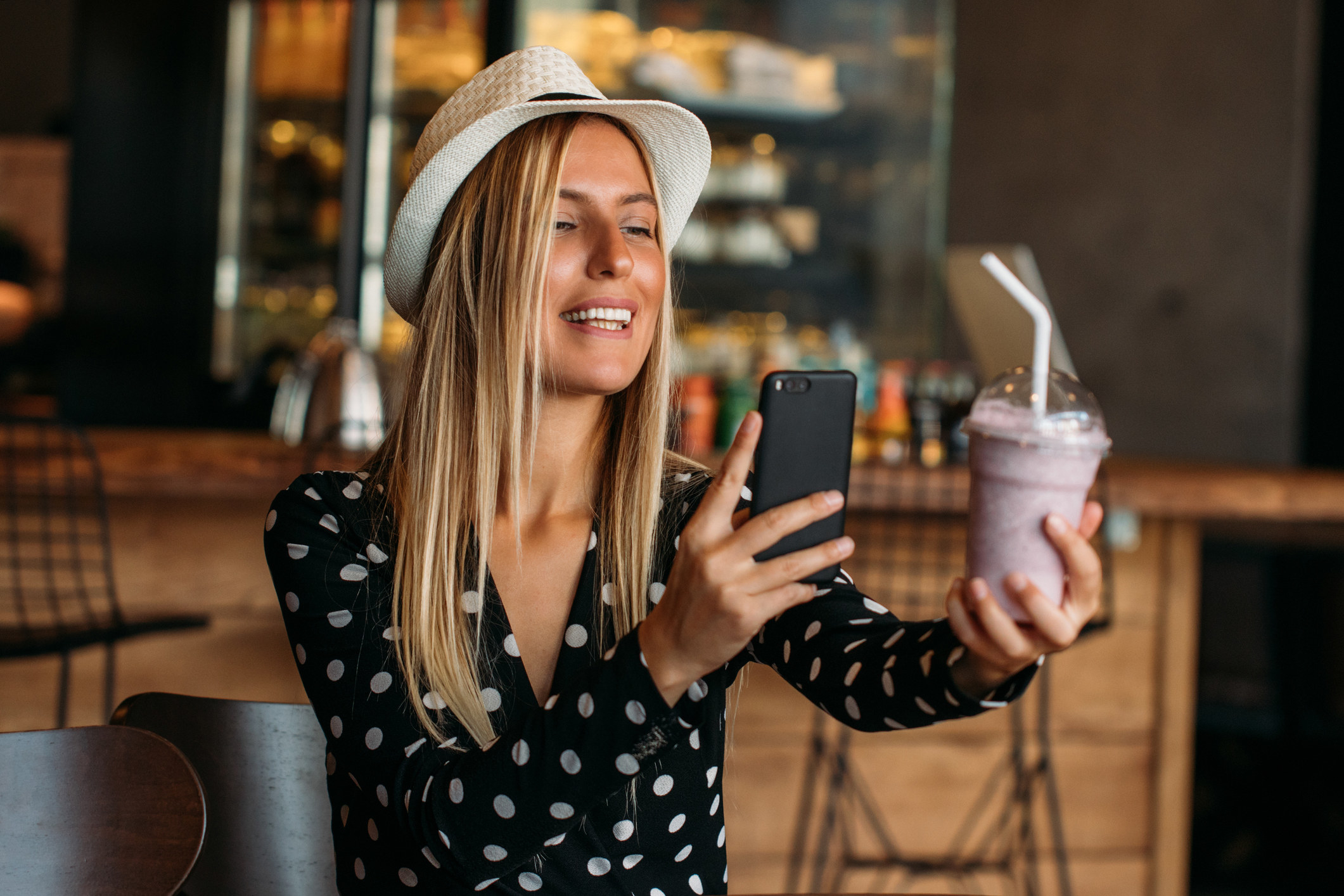 Woman holding a smoothie and taking a selfie