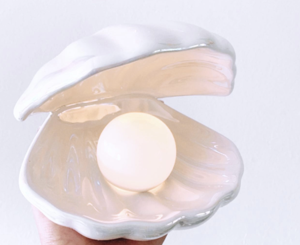 hand holding the iridescent shell lamp with pearl light glowing inside