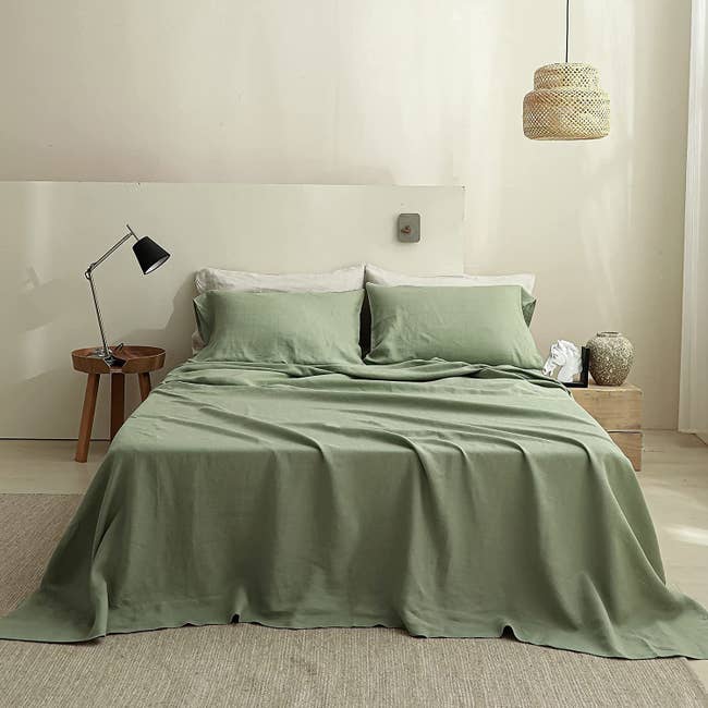olive green sheets on loosely made bed