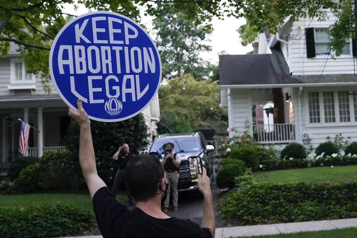 A protester standing in a street holds up a sign that reads "Keep abortion legal"