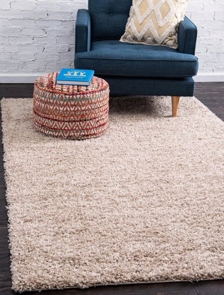 Beige rug on floor with blue chair