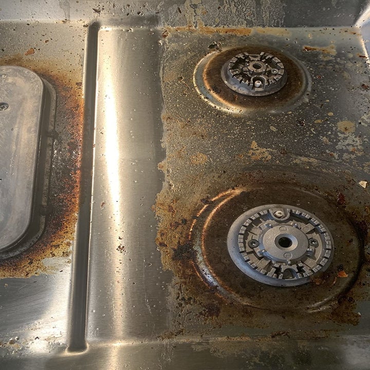 close-up photo of dirty gas burners that are coated in dark brown grime