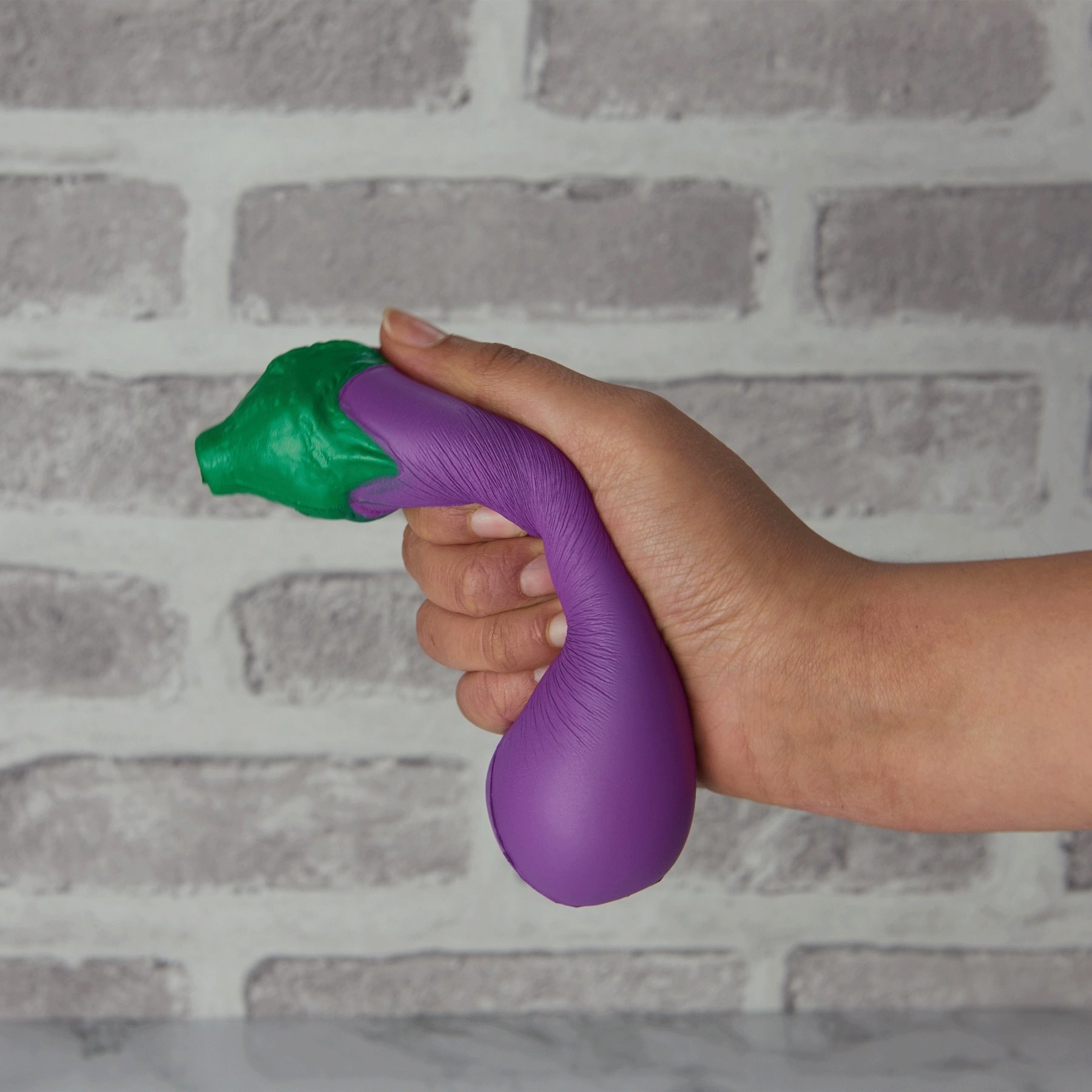 A person squeezing an eggplant stress toy
