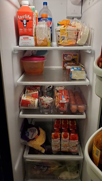 after photo of the same fridge with the food neatly stored in clear plastic bins and there's now a lot more room