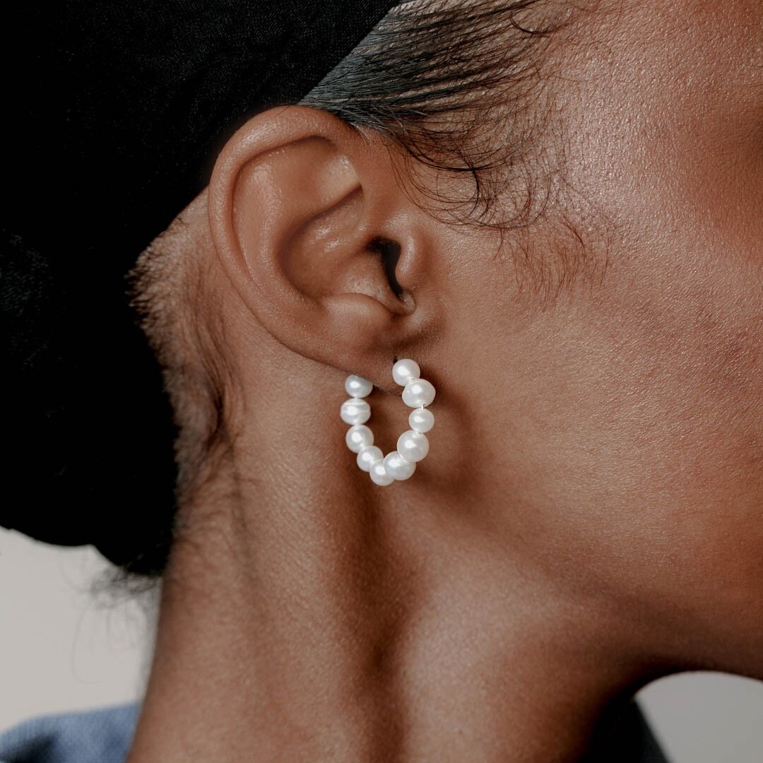 A person wearing a pearl hoop in their ear