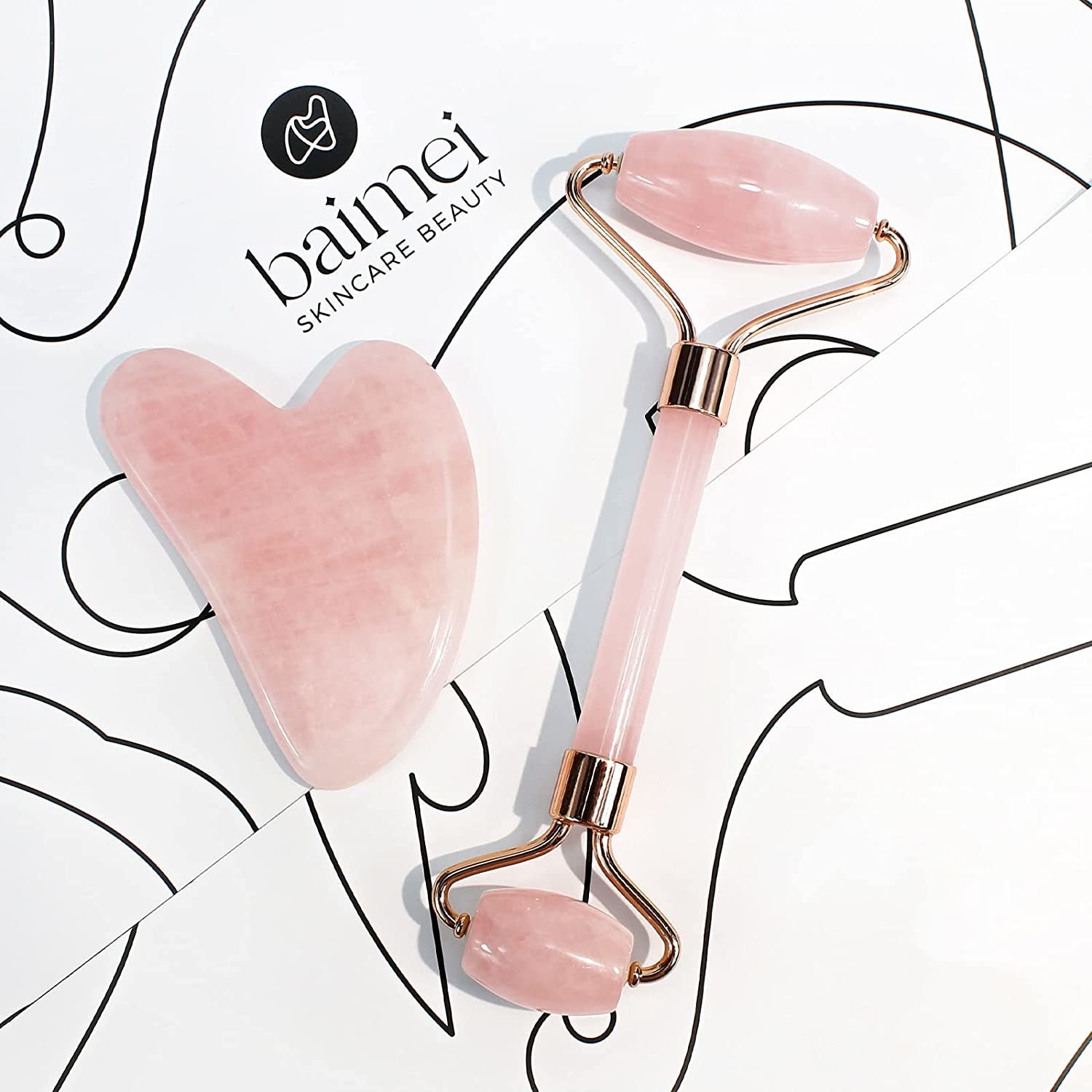the pink face roller and gua sha on a white background with simple line designs