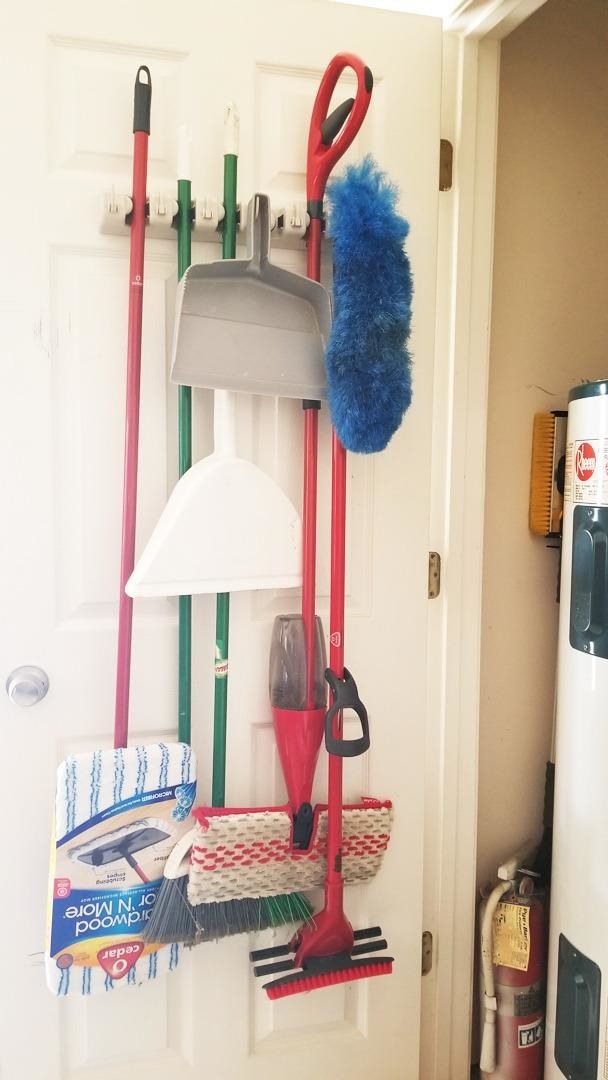 reviewer photo of a closet door with brooms, mops, and dustpans hanging from the tool