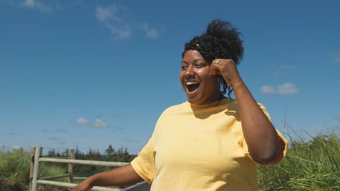 woman in yellow on the beach looking surprised