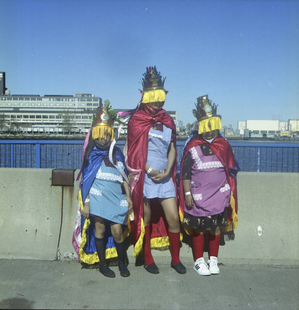 Three women in Indigenous garb standing in front of a river in NYC