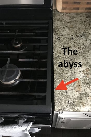a reviewer photo of the point where the stove meets the countertop with a red arrow pointing at the gap and text reading 