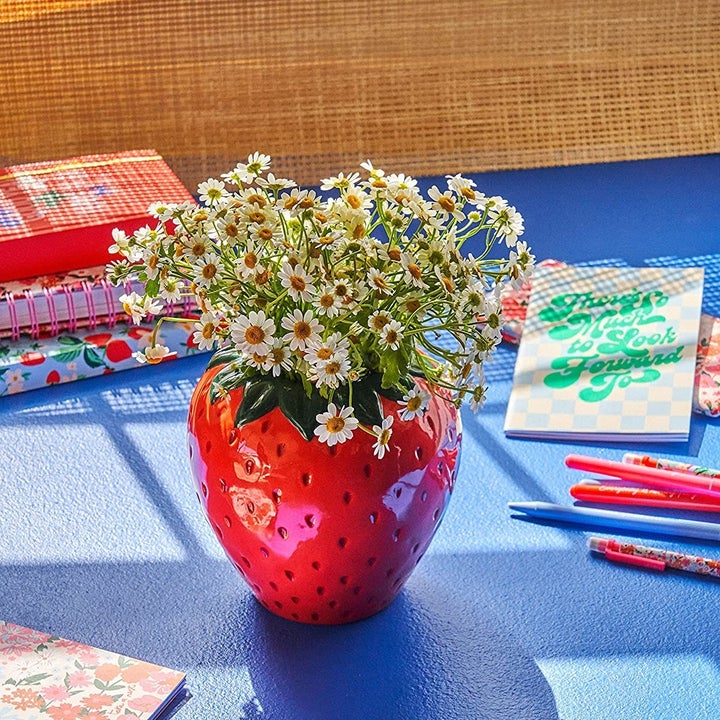 large strawberry shaped vase full of flowers 