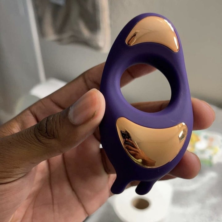 Reviewer holding purple and goldtone rabbit cock ring
