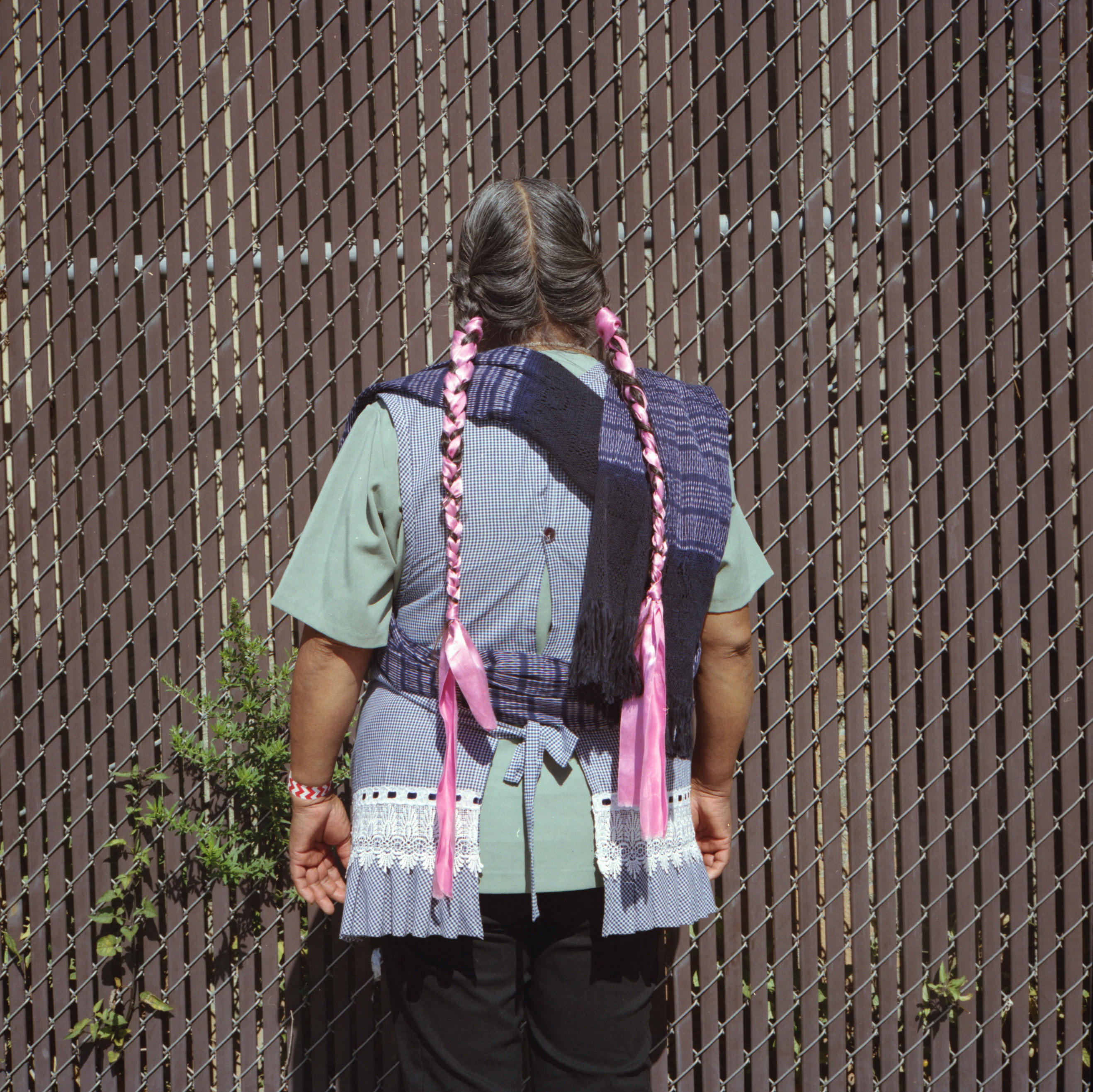 A woman photographed from behind with long braids and ribbons in her braids