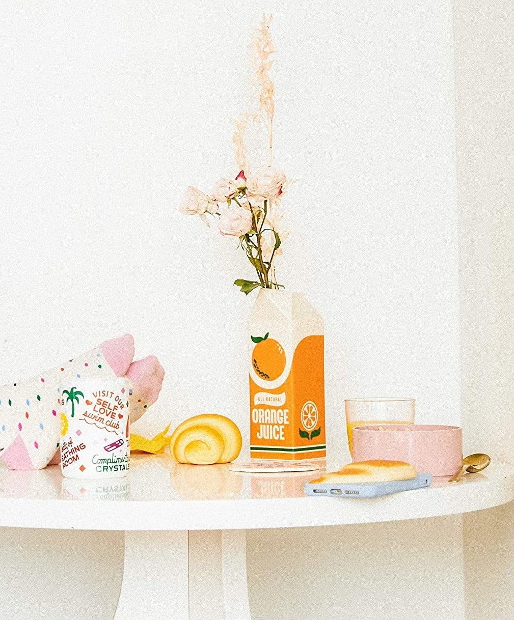 orange juice carton vase with a small amount of flowers placed on a table 