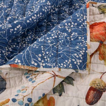 A closeup of the bedding shows that one side has a forrest creature pattern and the other has a blue flower pattern