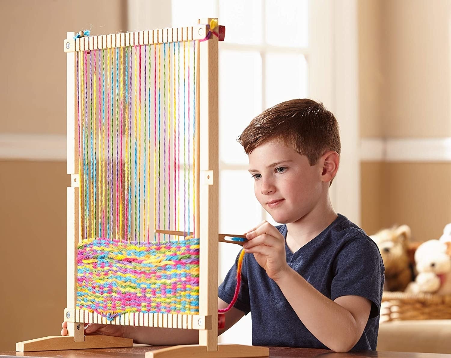 Child model playing with loom and colorful yarn