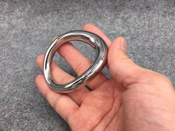 Model holding curved stainless steel cock ring