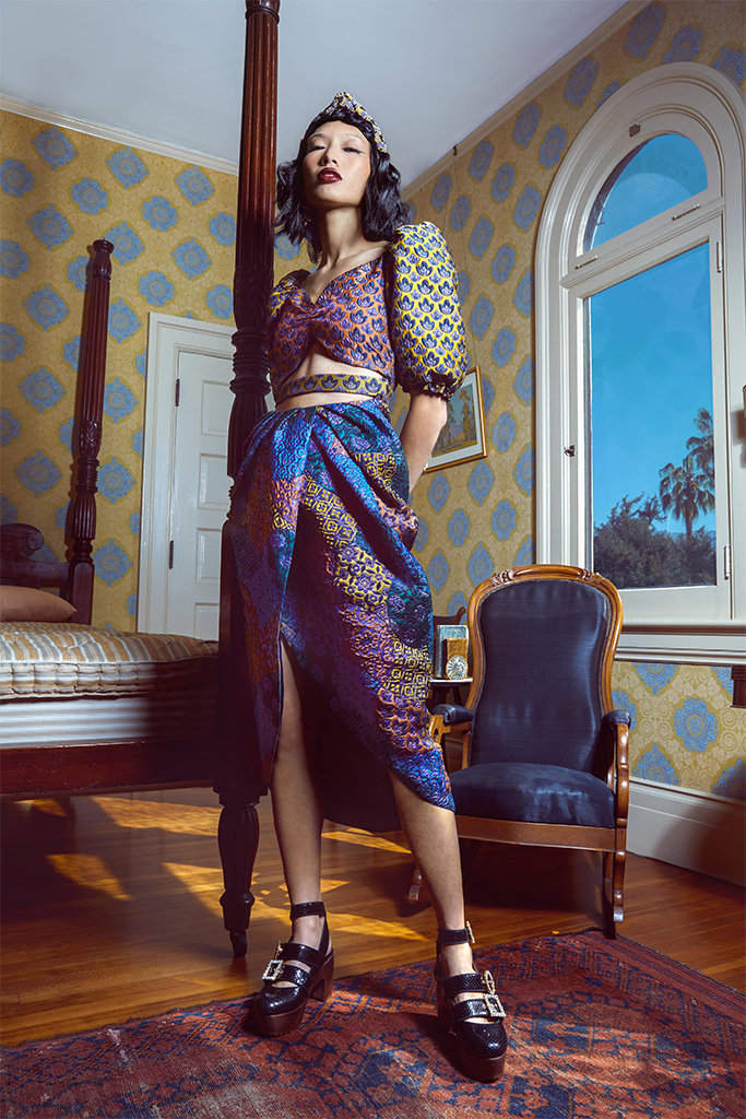 model in the multi pattern blue, orange, purple, and yellow midi with sweetheart neckline and elbow-length sleeves with cutouts at the waist
