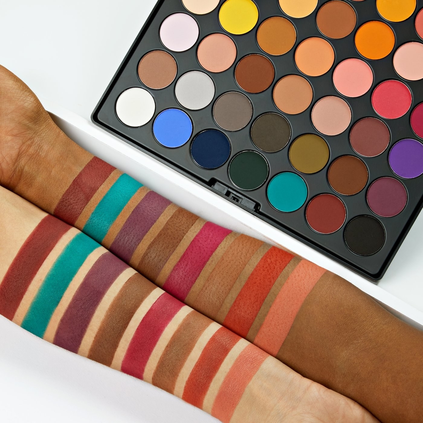 two models arms who are fair and dark-skinned with some of the shades swatchedon their arms to show that the colors look good on various skin tones