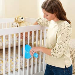 A model placing the blue pad under the crib mattress