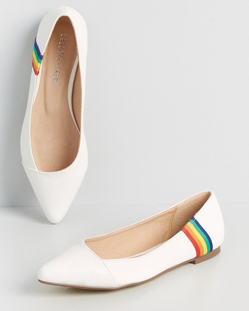 white pointy toe flats each with a grosgrain rainbow on the side of the heel