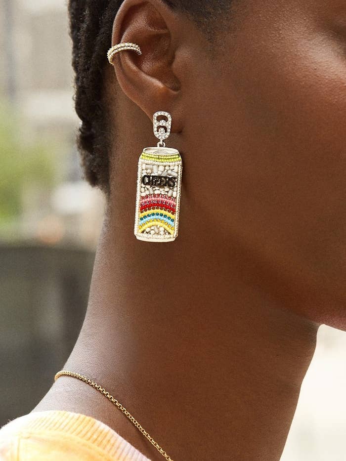 model in jeweled earrings that look like seltzer cans with the word &quot;cheers&quot; hanging from posts shaped like pop tops
