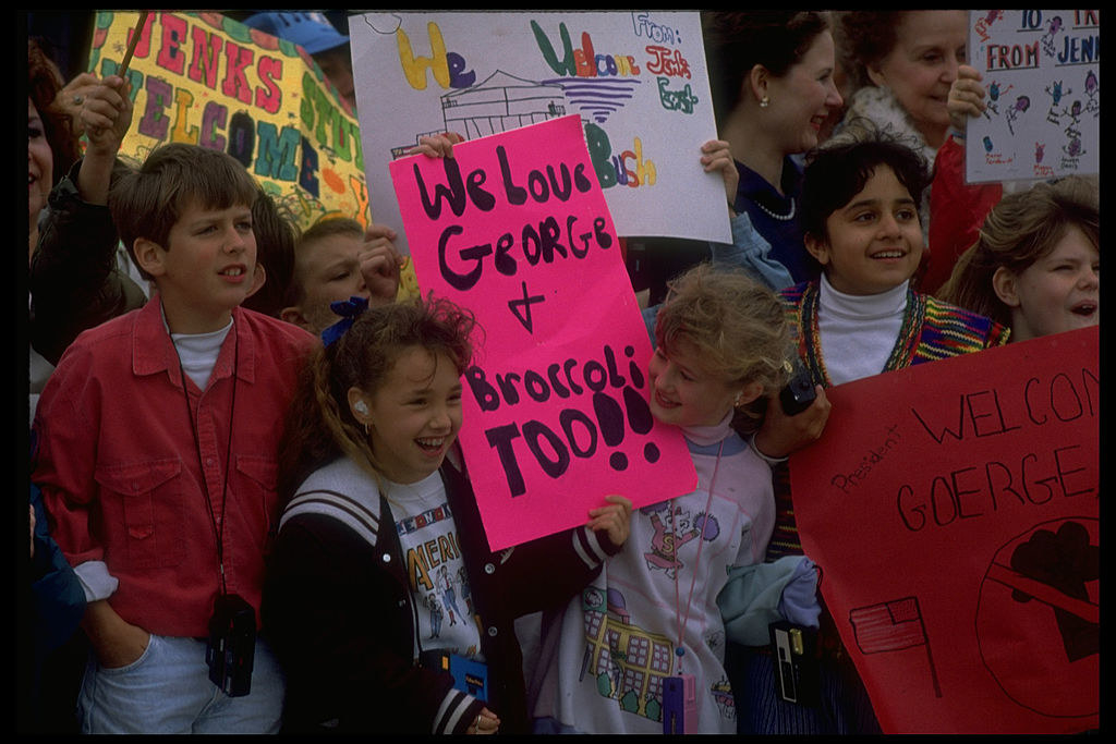 some kids hold a sign that says &quot;we love George and broccoli too!&quot;