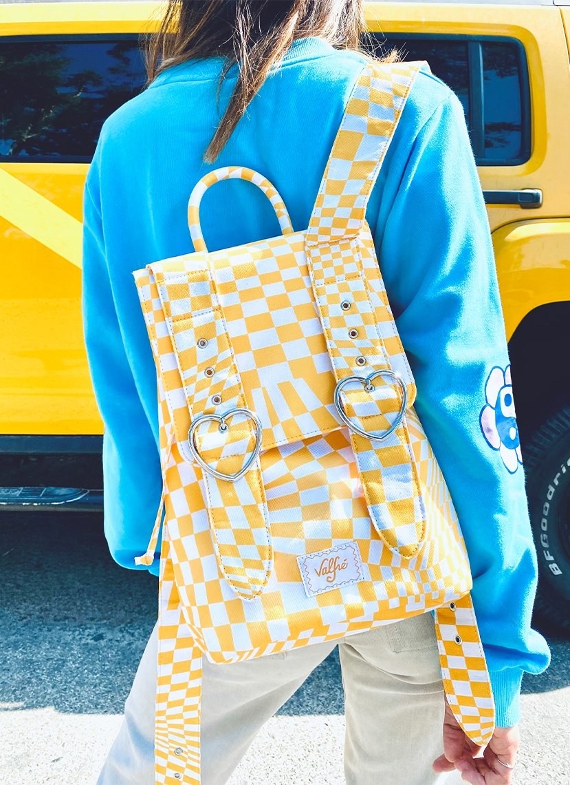 yellow-and-white checkered backpack with heart-shaped buckles