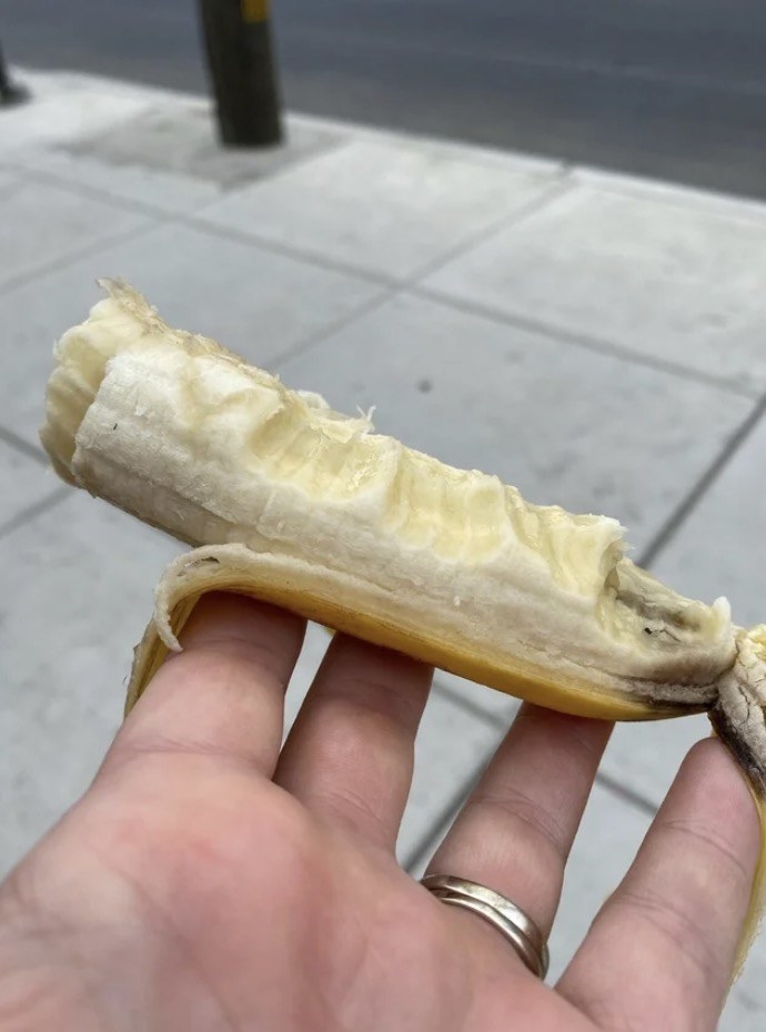 A half-peeled banana with random bites along it lengthwise, held in someone&#x27;s hand