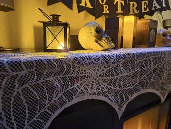 reviewer's mantel with the white decoration on it with Halloween decorations on top