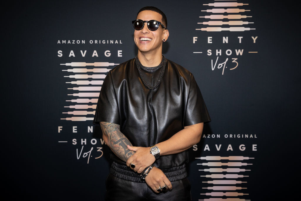 Daddy Yankee smiles on the red carpet while wearing a leather-like shirt with satin pants