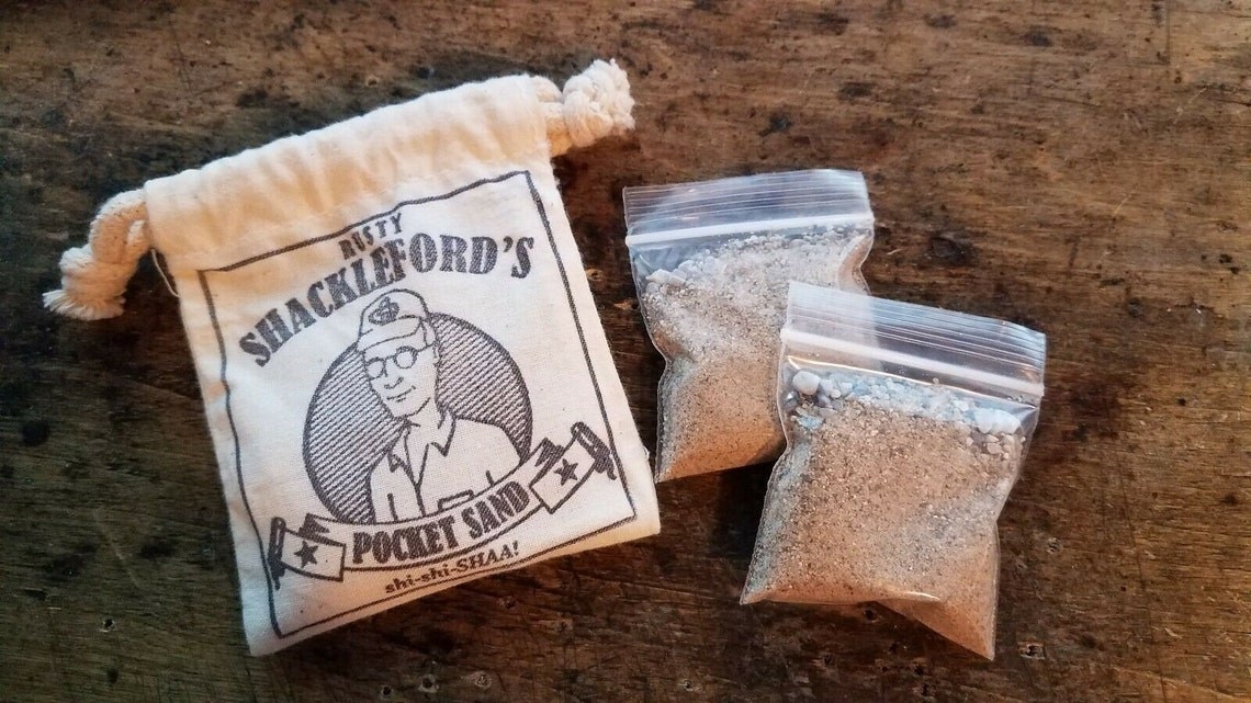 bag of sand that says rust shackleford&#x27;s pocket sand with a picture of dale gribble from king of the hill