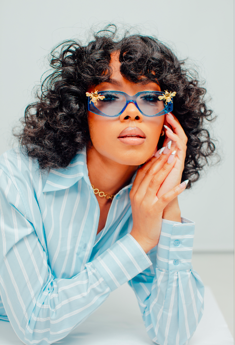 model wearing light blue sunglasses with gold bees attached to the sides of the frame