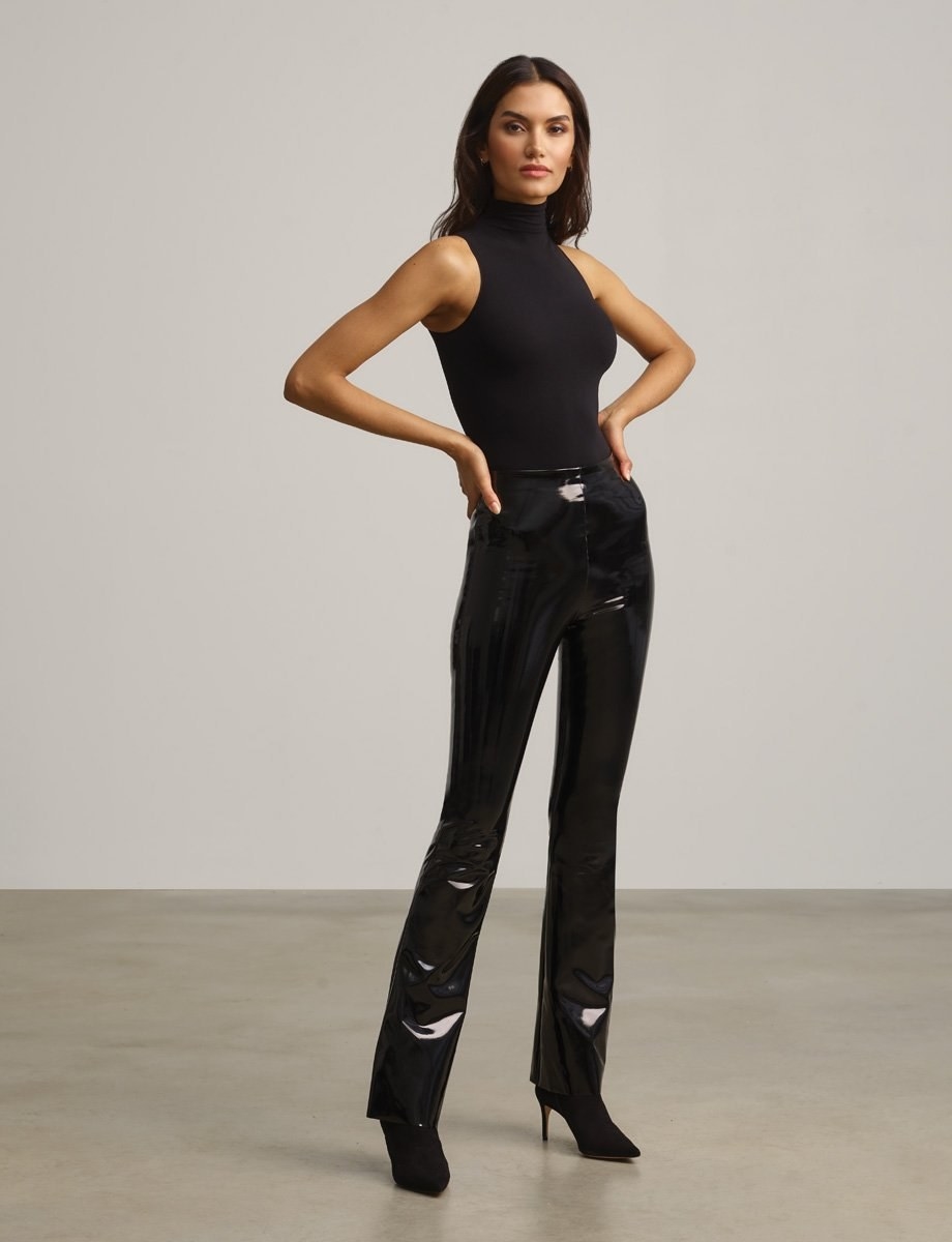 Model wearing black faux leather flare leggings