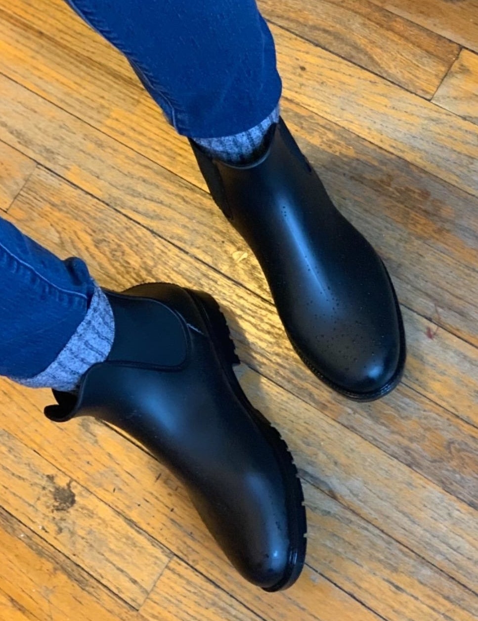 a reviewer photo of someone wearing the boots with thick gray socks and jeans 
