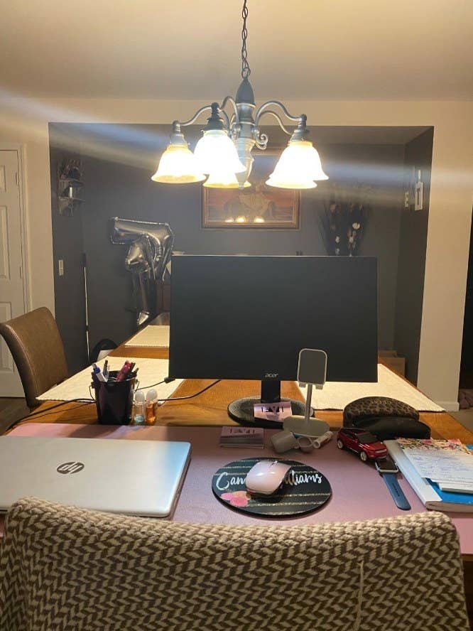 Pink desk pad on dining table with notebooks, laptop, mouse pad