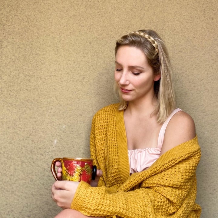 reviewer wearing the mustard yellow cardigan while holding a cup of tea