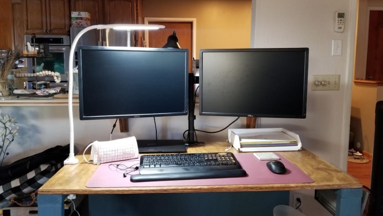 Gooseneck white clip on lamp over desk with two computer monitors