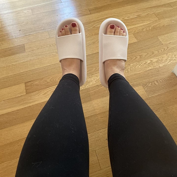 a reviewer wearing black leggings and a tan pair of the open-toed slippers 